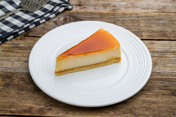 caramel cheesecake on white plate on wooden table