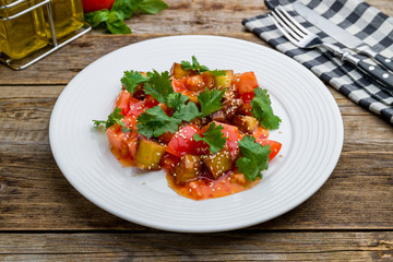 fried eggplant in sweet sour sauce with tomatoes on wooden table