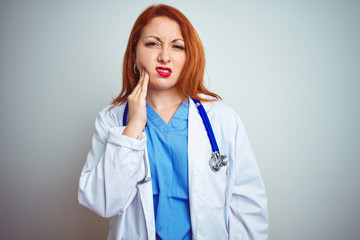 Young redhead doctor woman using stethoscope over white isolated background touching mouth with...