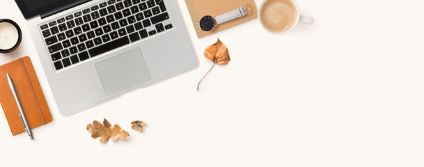 Autumn or fall styled home office workspace banner / header with laptop computer, dry leaves , cup...