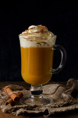 pumpkin latte with whipped cream in a glass jar on a rustic background