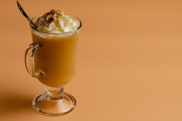 pumpkin latte with whipped cream in a glass jar on a colored background