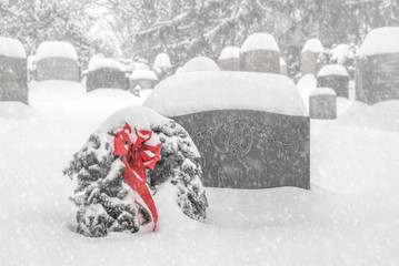Red wreath in snow, cemetery by gravestones nobody