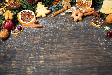 Christmas background with Christmas tree branch, festive decoration, dry fruits, home made cookies and traditional seasonal spices, top view