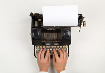 Man typing on vintage retro typewriter on white table background top view flat lay from above -...