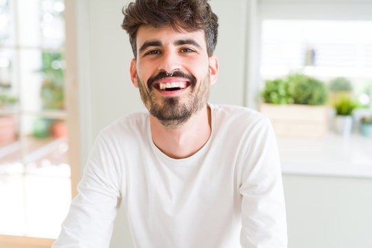 Handsome young man smiling cheerful at the camera with a big smile on face showing teeth