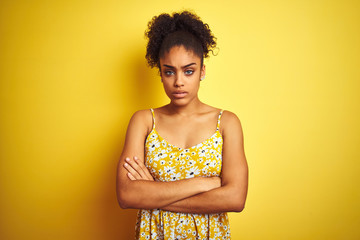 African american woman wearing casual floral dress standing over isolated yellow background skeptic...
