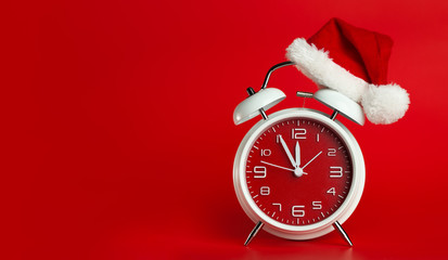 Red clock with Christmas Santa hat. Time for Christmas shopping concept. Blank red space for text.