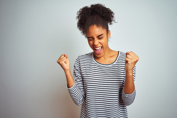 African american woman wearing navy striped t-shirt standing over isolated white background very happy and excited doing winner gesture with arms raised, smiling and screaming for success