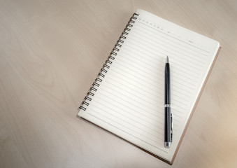 black pen with blank pages on soft brown wooden table  background