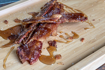 candied bacon with salt served on a wooden serving tray