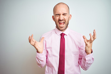 Young business man wearing pink tie over isolated background celebrating mad and crazy for success with arms raised and closed eyes screaming excited. Winner concept