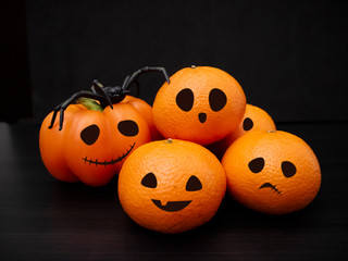 Halloween decorations with pumpkin and clementines on dark background.