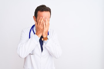 Fototapeta premium Middle age doctor man wearing coat and stethoscope standing over isolated white background with sad expression covering face with hands while crying. Depression concept.