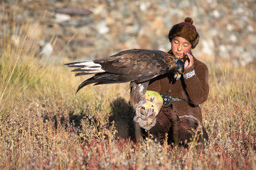 Traditional kazakh eagle huntress with her golden eagle that is used to hunt for fox and rabbit...