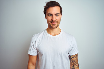 Obraz premium Young handsome man with tattoo wearing casual t-shirt over isolated white background with a happy and cool smile on face. Lucky person.