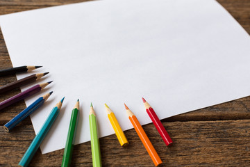 colorful colored pencil and white paper  on wooden background