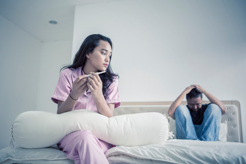 Fototapeta premium Sad teenage couple with pregnancy test on bed