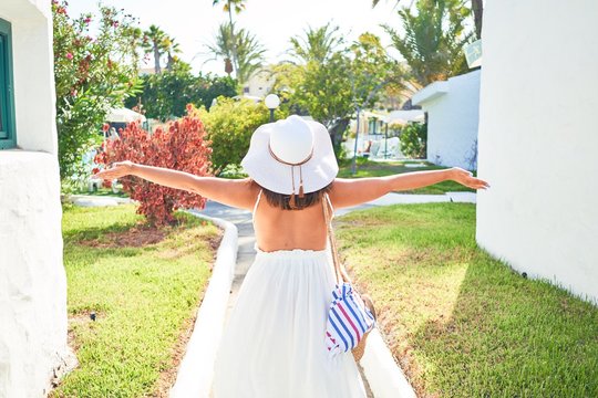 Young beautiful woman on white houses village walking on the streets on a sunny day of summer