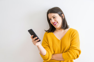 Beautiful brunette young woman smiling confident using smartphone over isolated white background wearing casual yellow sweater