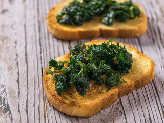 Toasted bread with roasted herbs on a wooden table.