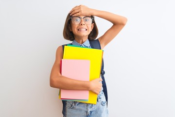 Beautiful student child girl wearing backpack glasses books over isolated white background stressed with hand on head, shocked with shame and surprise face, angry and frustrated. Fear and upset.