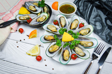 Mussels with herbs in pot with orange lemon parsley tomato in the table setting - Steamed mussels green shell served on white plate seafood sauce delicious on dining table restaurant