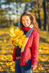 Young beautiful woman enjoys sunny autumn day in the park