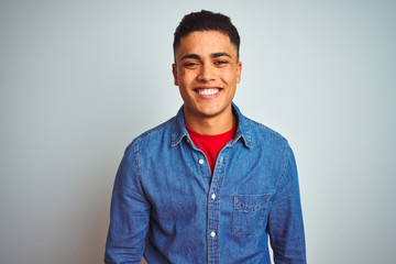 Young brazilian man wearing denim shirt standing over isolated white background with a happy and...