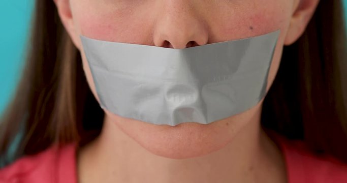 Crop face of woman with gray duct tape over mouth being deprived of speech