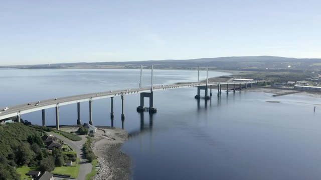 An aerial view of Kessock Bridge in Inverness on a sunny summer's morning. Rising shot with tilt down towards the western side of the bridge whilst zooming in.