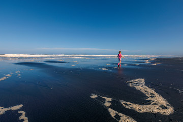 Little girl walking on the black beach in the morning, New Zealand