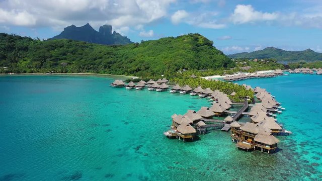 Aerial drone video of Tropical vacation paradise island with overwater bungalows in coral reef lagoon ocean beach. Mount Otemanu, Bora Bora, French Polynesia, Tahiti, South Pacific Ocean.