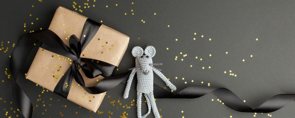 Mouse is a Symbol of new year 2020. Toy mouse and stylish gift box with black bow on black background. New year and Christmas concept. Copy space.