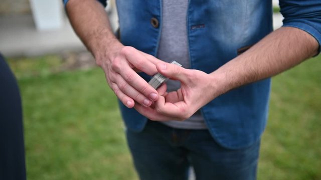 Close up illusionist in red shirt perform playing cards magic tricks. Summer day