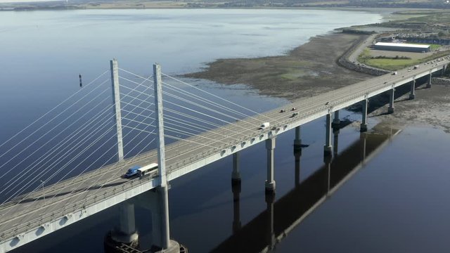 An aerial view of Kessock Bridge in Inverness on a sunny summer's morning. From above the western side of the bridge whilst flying away whilst zooming out.