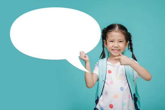 Excited young Asian little girl with empty speech bubble, empty space in studio shot isolated on colorful blue background, Educational concept for school