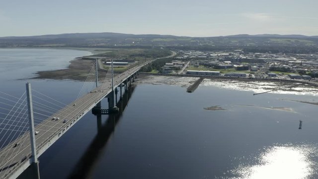 An aerial view of Inverness with the Kessock Bridge to the left of frame on a sunny summer's morning. Flying past the bridge with Inverness in the background.