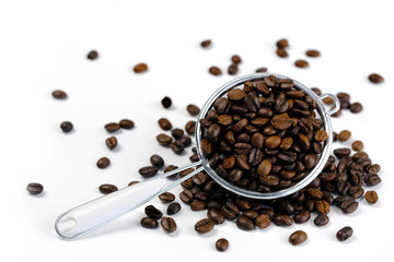 Roasted  coffee seeds in metal colander on white background.