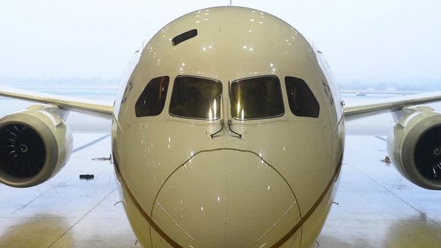 787 widebody aircraft stationary in hangar with beacon light flashing.