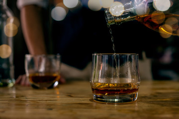 glass of whiskey and ice on wooden table