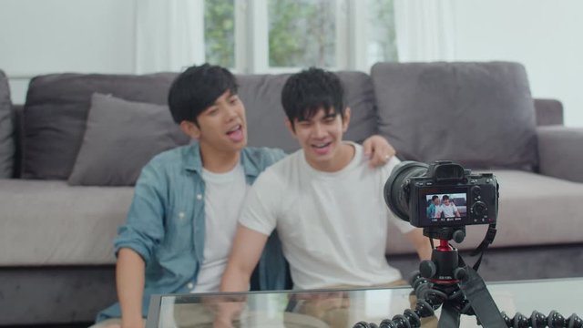 Young Asian gay couple influencer couple vlog at home. Teen korean LGBTQ men happy relax fun using camera record vlog video upload in social media while lying sofa in living room at house. Slow motion