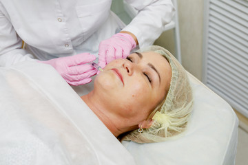 Fototapeta na wymiar Beautician doing facial injection. Anti-aging revitalization cosmetology procedure