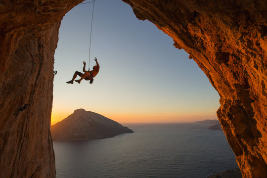 Silhouette of a climber falling on a rope above the Mediterranean sea with another island in view.. 
