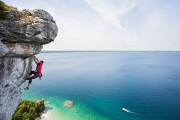 Rock climbing a steep cliff high above a large lake.