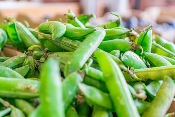 Pile of green snap peas (pea pods) being sold at a farmer's market.