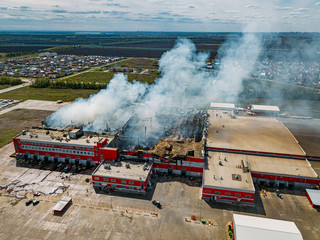 Fototapeta premium Burning industrial distribution warehouse, aerial drone view