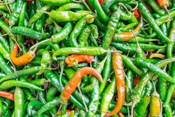 Close up background of cayenne peppers in green and some red, being sold in a farmer's market.