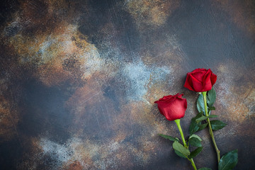 Red roses lie on a textured spotted marble background. A sign of condolence, sympathy for the loss. Space for your text.