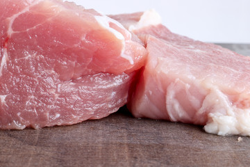 Large slices of pork on an old wooden surface. The concept of cholesterol food. Raw meat before cooking. Copy space.
